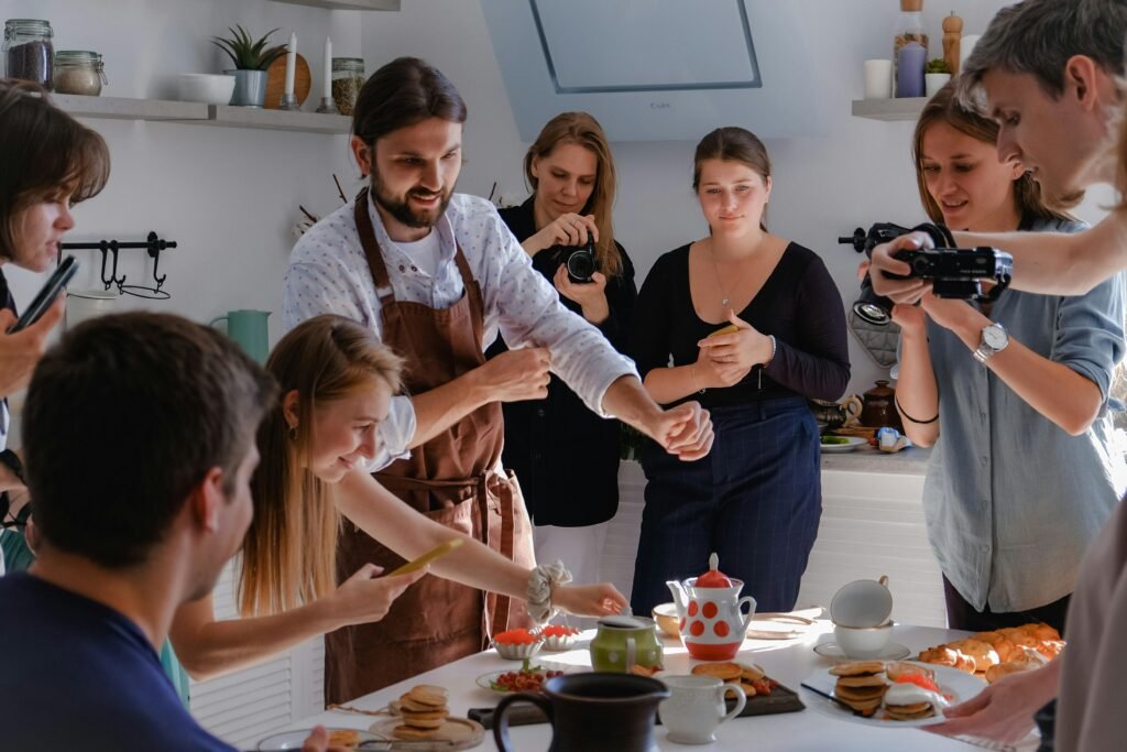 People participating in a lively photoshoot around a table in a bright kitchen.